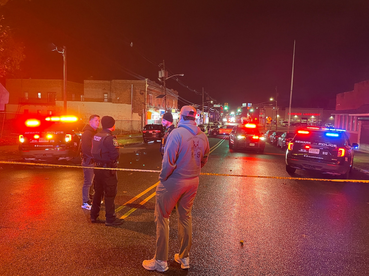 Police talk at the perimeter of a crime scene during an investigation into a shooting at the intersection of Chancellor Avenue and Leslie Street in Newark, Saturday, Nov. 15, 2025.