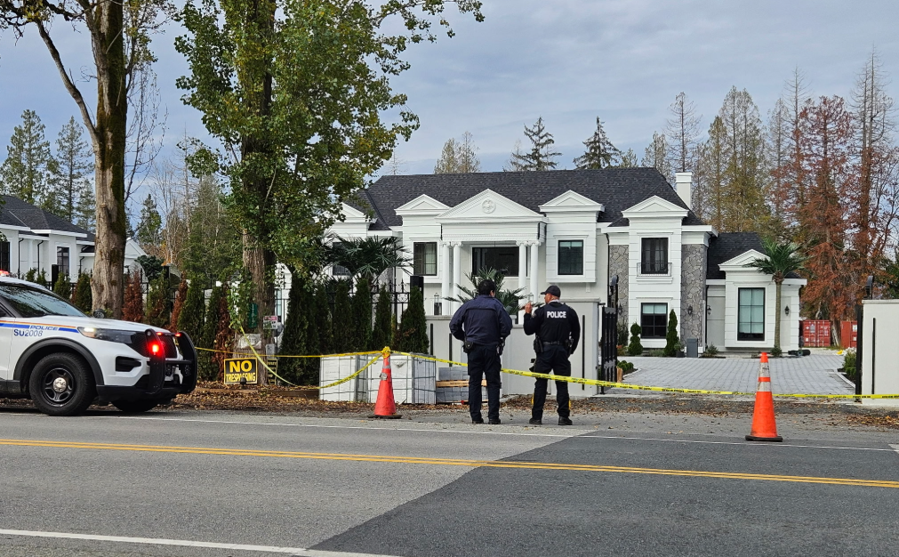Police officers investigate a shooting outside a Surrey home