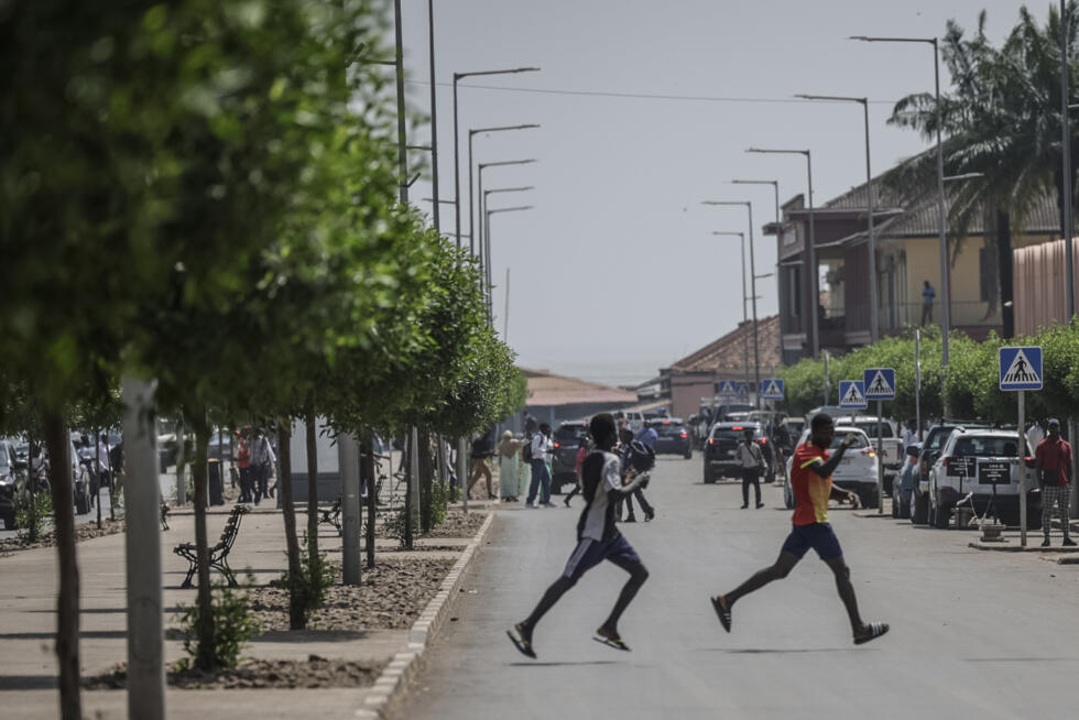 Men flee the scene as gunfire rings out near the presidential palace in Bissau on November 26, 2025