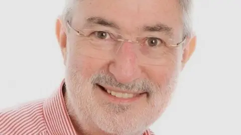 Family handout Ray McMahon has a a red and white striped shirt. He wears small spectacles, has short grey hair and white stubble.