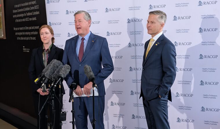 A woman and two men stand at a press conference.