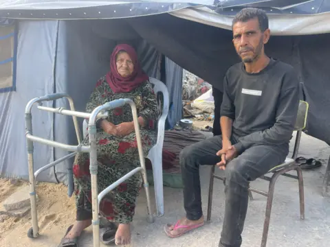 Palestinian Rami Deif Allah (right) sits with a female relative outside the front of their tent