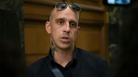 AFP via Getty Images Georgi Filipov, 35 - one of the three suspects linked to the defacing of the Paris Holocaust memorial - speaks to journalists in a court in Sofia on 7 August 2024. Three Bulgarian men were tracked down and arrested on suspicion of defacing the Paris Holocaust memorial in mid-May, Bulgaria's state security agency (SANS) announced.