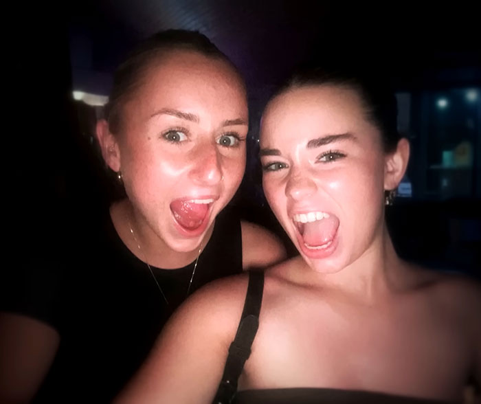 Two young women smiling widely in a dark setting, related to parents warning against travel after daughters' deaths.