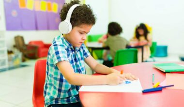 A young boy wears headphones inside a kindergarten classroom.