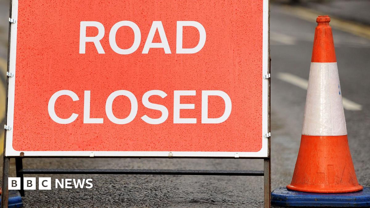 Red road closed sign with cone