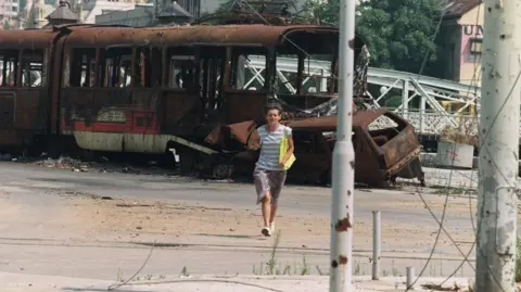 MICHAEL EVSTAFIEV/AFP A Bosnian woman runs in the street through an area usually targeted by Serbian snipers in downtown Sarajevo on August 4, 1993