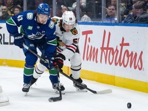 Vancouver Canucks' Quinn Hughes (43) and Chicago Blackhawks' Tyler Bertuzzi (59) vie for the puck during the first period of an NHL hockey game in Vancouver, on Wednesday, November 5, 2025.