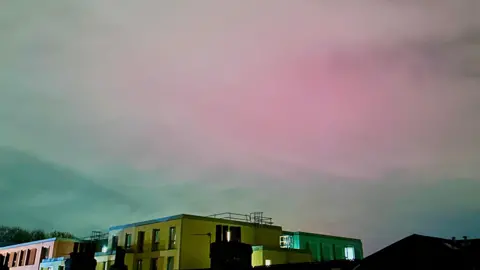 Kyaw A faint pink glow through the clouds over houses in Manchester