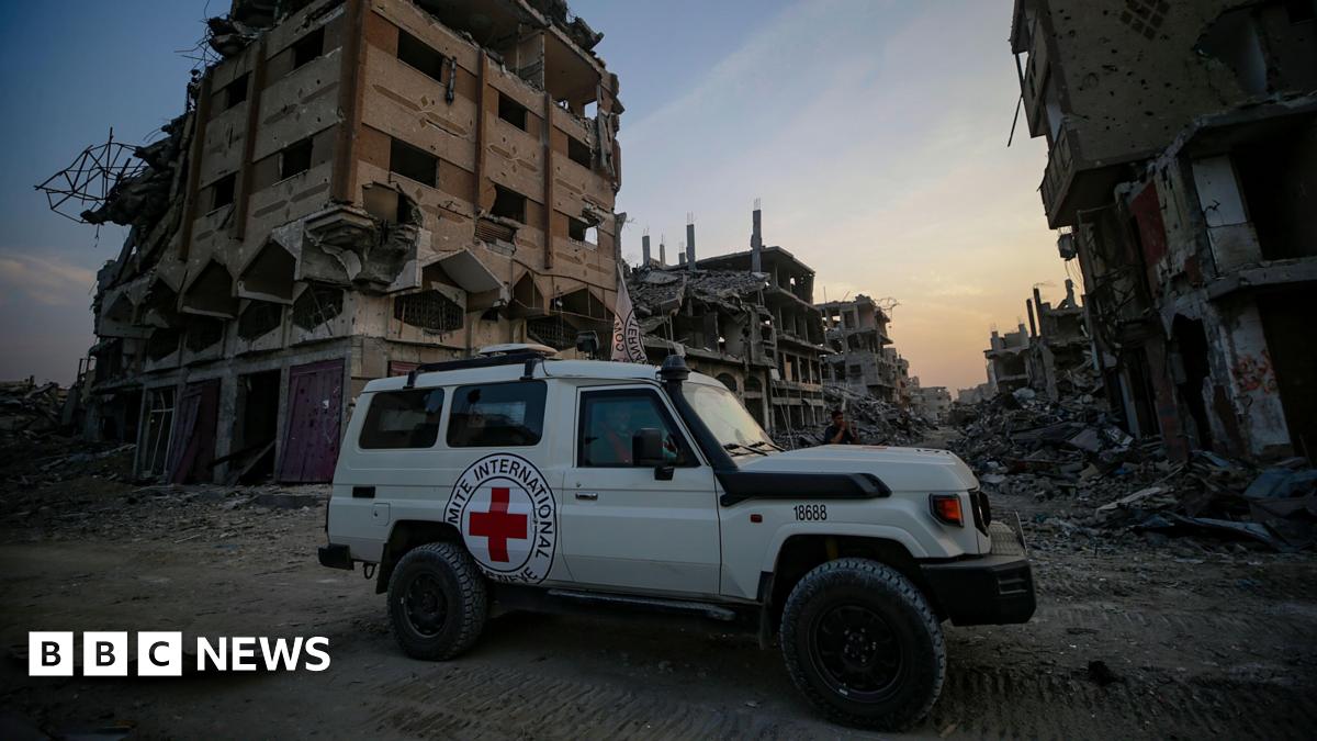 A white Red Cross jeep with the NGO's logo and a red cross emblem is seen in front of damaged and destroyed buildings, the sun setting in the background, as workers assist as fighters of the Al-Qassam Brigades, the military wing of the Hamas movement, search for the bodies of Israeli hostages in Al Shejaeiya neighbourhood in the east of the Gaza City, Gaza Strip.