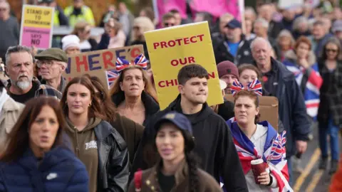 Eddie Mitchell People standing with Union Jack flags and placards.