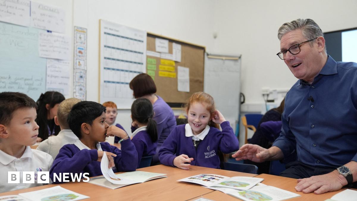Britain's Prime Minister Keir Starmer wears a dark blue shirt and reads with pupils during a visit to Welland Academy, to talk about the importance of free school meals and tackling the cost of living.