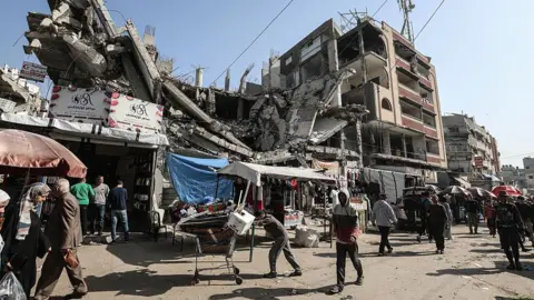 Anadolu via Getty Images Palestinians shop at a local market in Nuseirat refugee camp, in Deir al-Balah, central Gaza (19 November 2025)