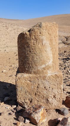 A crumbling stone pillar in a desert landscape