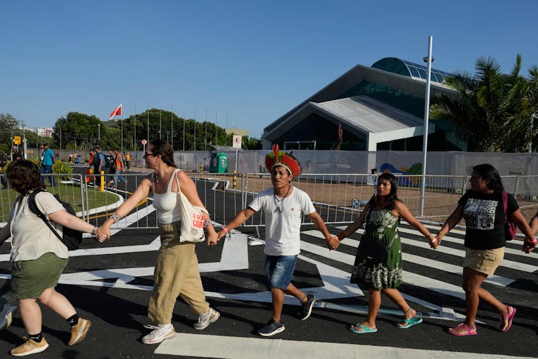 A group of people walk along holding hands in protest at a climate summit.