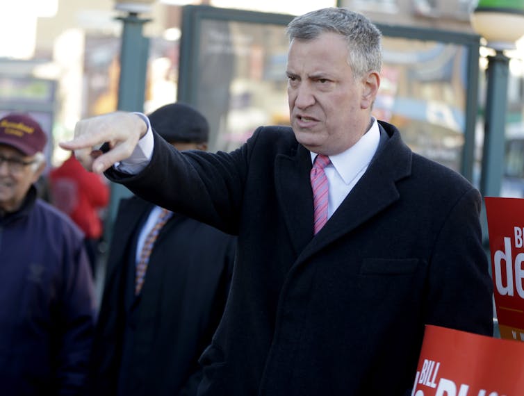 A man in a coat points his finger at someone.