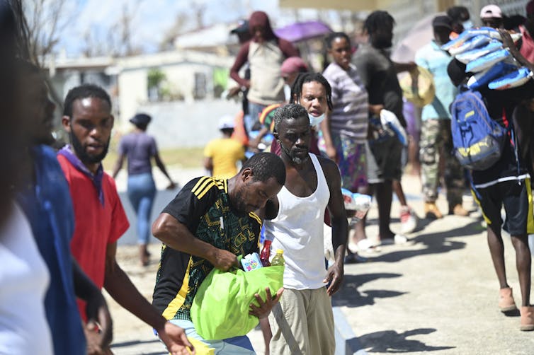 A line of people pass bags of food items one to another.