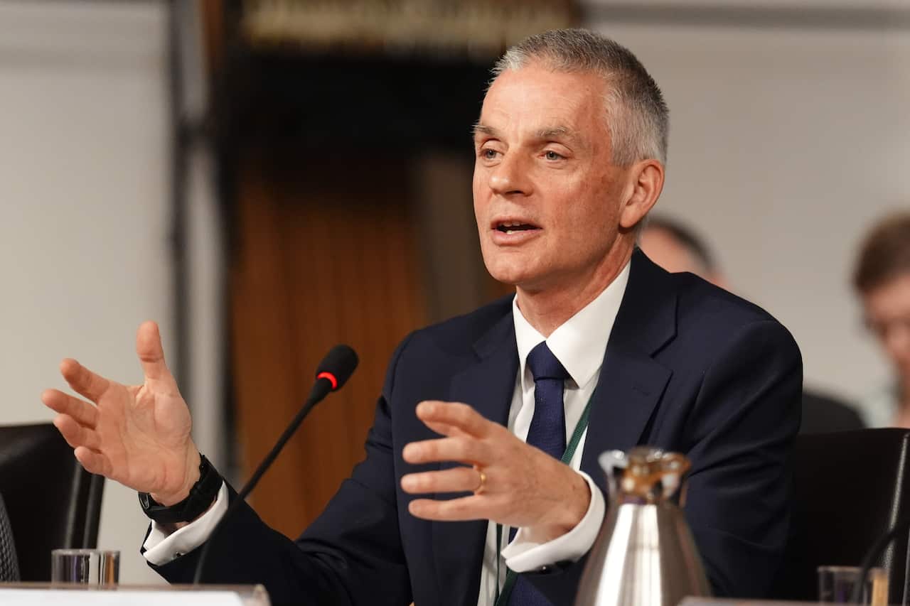 A man speaking in front of a microphone while sitting down