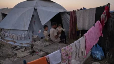 Mohammed Barabakh sits on a grave with his children at the entrance to his tent, that was set up in a cemetery in Khan Younis, in the southern Gaza Strip, Friday, Oct. 31, 2025. Photo: AP Photo/Abdel Kareem Hana via UNB