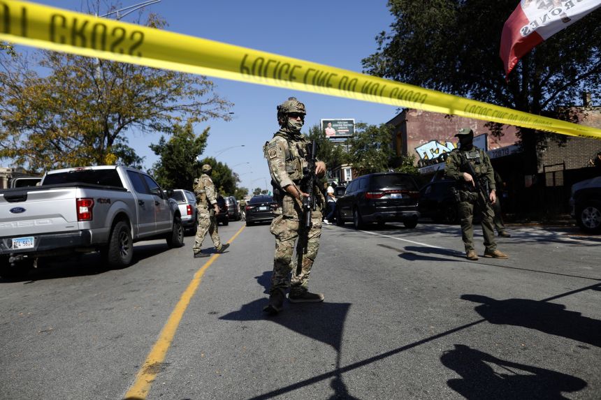 Masked US Customs and Border Protection Border Patrol agents stand behind a police line as residents of Chicago's Brighton Park neighborhood confront law enforcement at a gas station after Immigration and Customs Enforcement allegedly detained an unidentified man riding in his car on October 4.