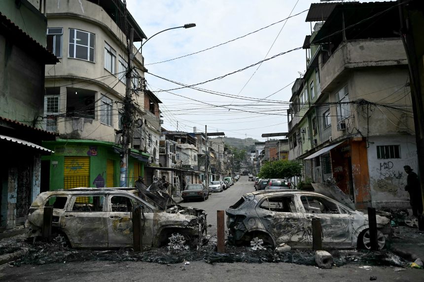 A man stands next to cars burnt during a barricade in Rio's Complexo da Penha on October 28.