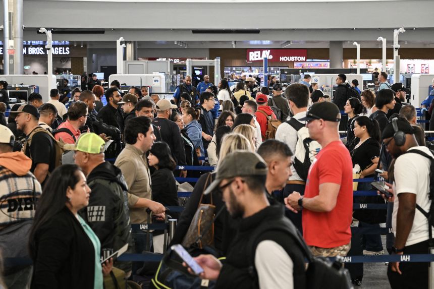 Travelers wait in line at a security checkpoint at George Bush Intercontinental Airport in Houston, Texas on November 7, 2025.