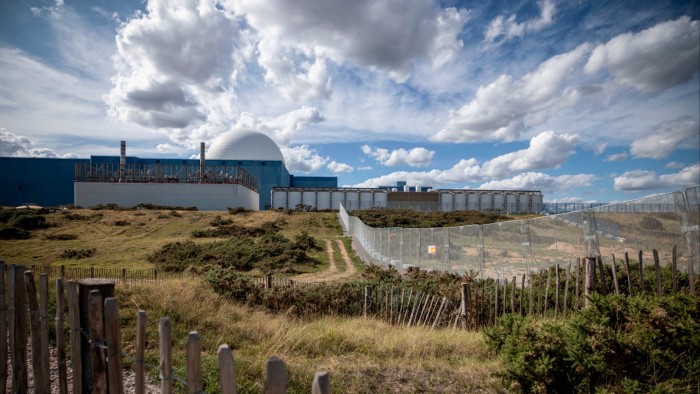 Sizewell C reactor construction site with fencing and earthworks in the foreground; Sizewell B's white dome visible behind.