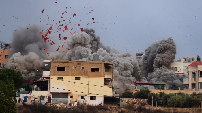 Smoke and debris rise from behind buildings after an airstrike in Teir Debba, southern Lebanon.