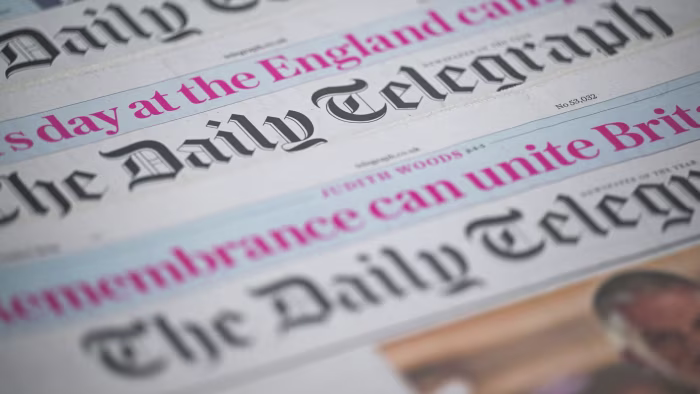 Several copies of The Daily Telegraph newspaper are shown in close-up, focusing on the masthead and partial headlines.