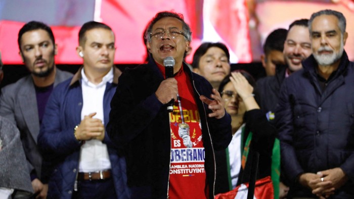Colombia’s President Gustavo Petro speaks into a microphone at a rally, surrounded by several people on stage at Bolivar Square in Bogotá.