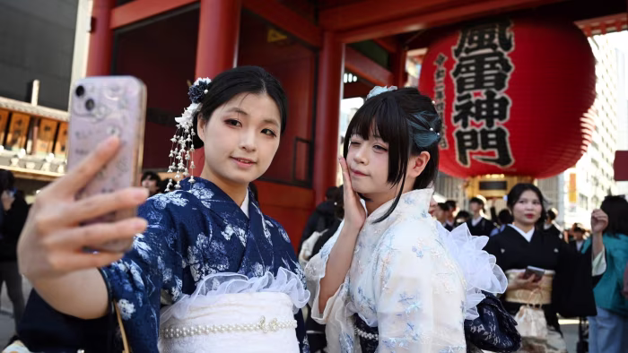 Two women in kimonos take a selfie in front of the large red lantern at Sensoji Temple in Tokyo’s Asakusa district