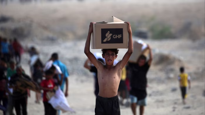 A Palestinian boy carries a box of food provided by the Gaza Humanitarian Foundation