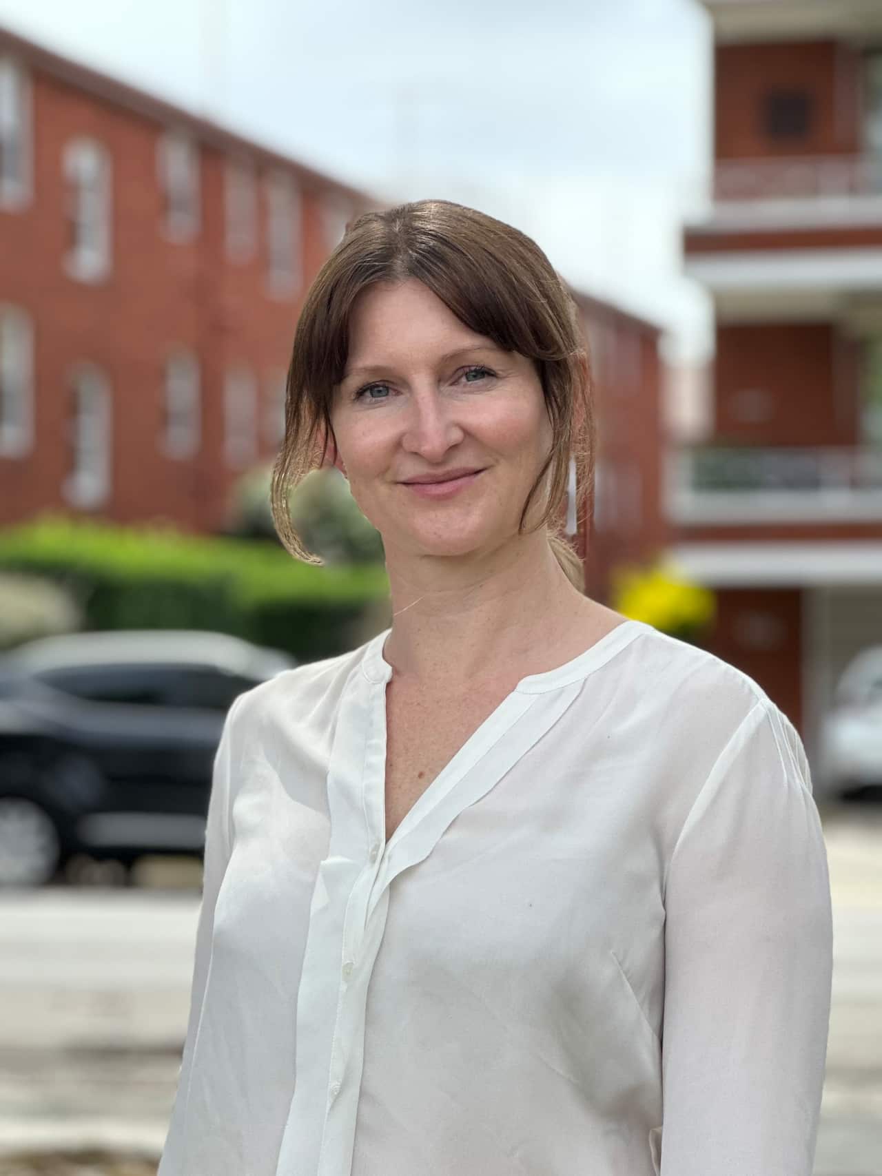 Photo of lady dressed in white top, in the foreground of rental units in Sydney.