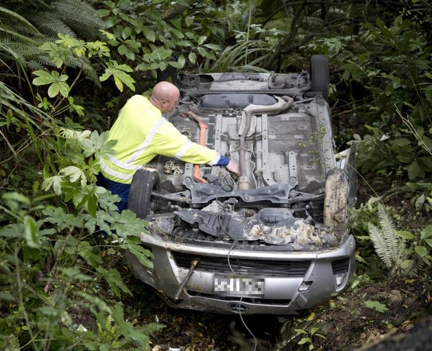 A Reilly's tow truck operator attaches a cable to a car that slid off a sharp corner on Cosy Dell...