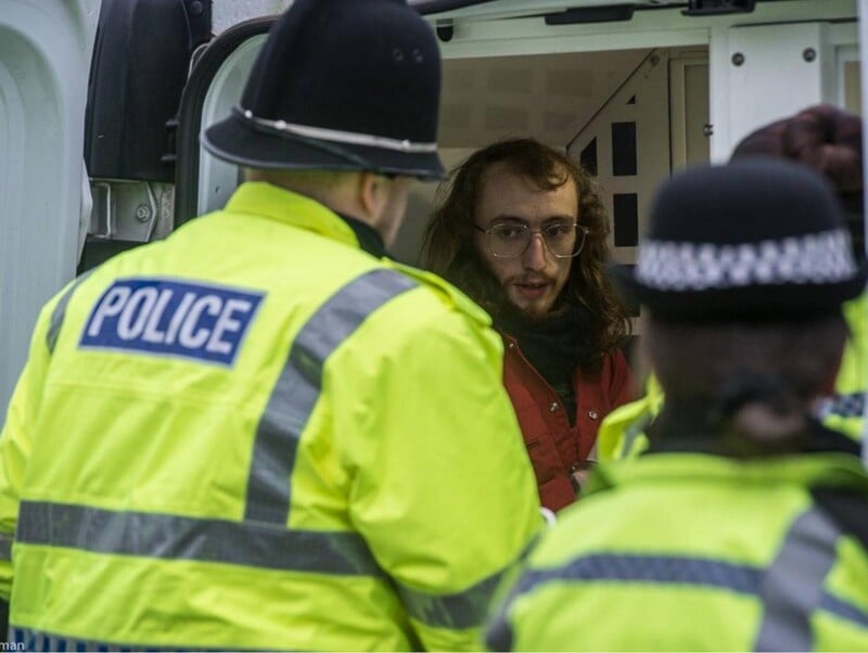 A man being put into a van by UK police