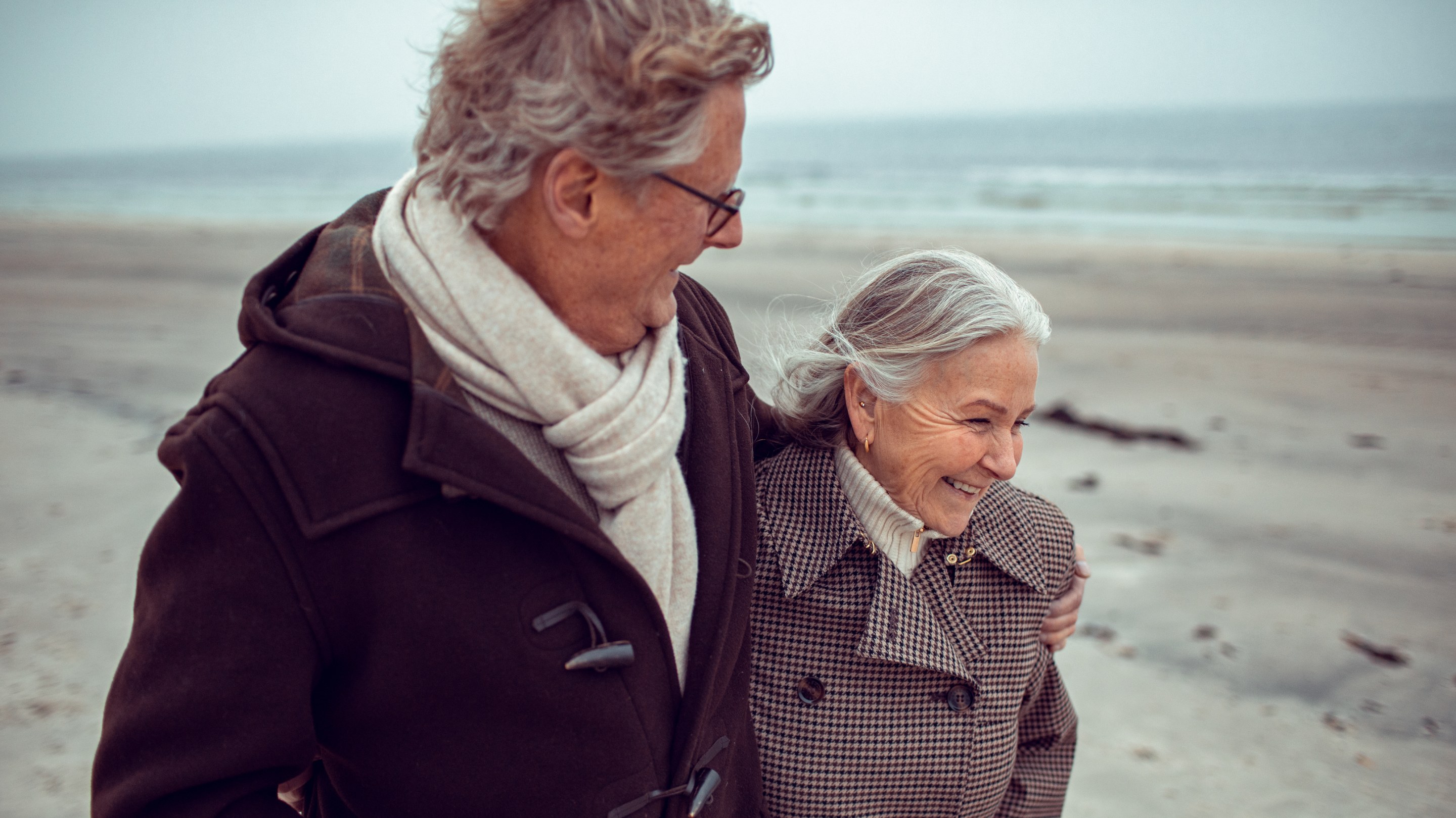 Senior couple strolling along a beach in winter