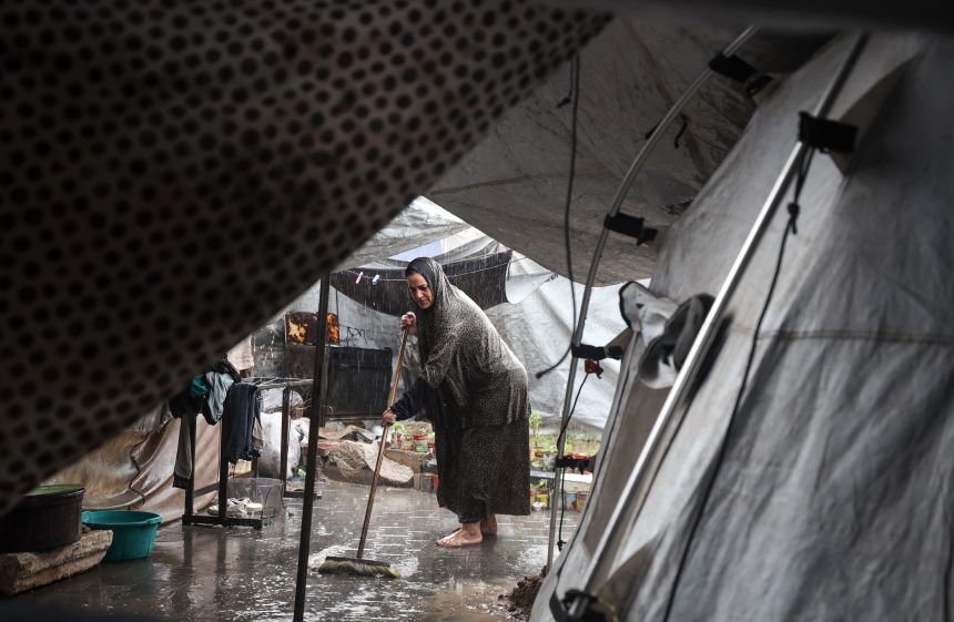A displaced Palestinian woman pushes water away from her tent after heavy rainfall at a makeshift camp inside Gaza's port during a rainstorm in Gaza, Palestine, on Friday.