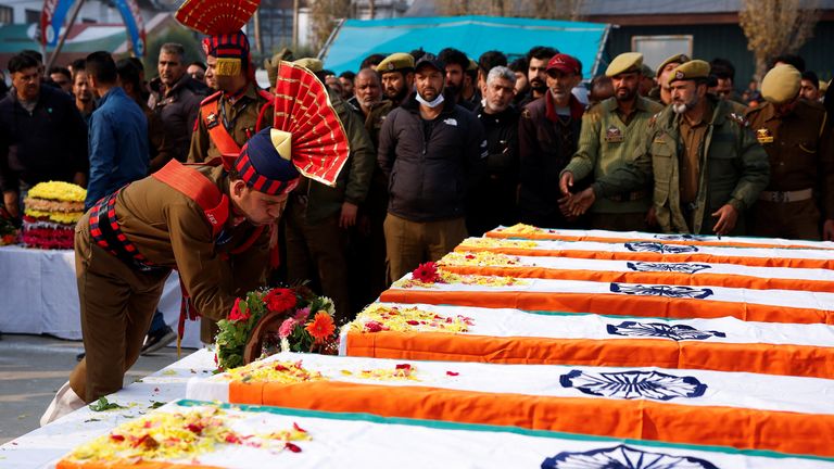 A police official lays flowers on a coffin at a ceremony for the victims. Pic: Reuters 