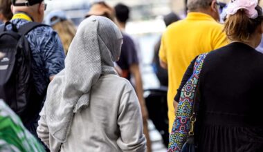 Rear view of woman wearing hijab walking in crowd of people, background with copy space
