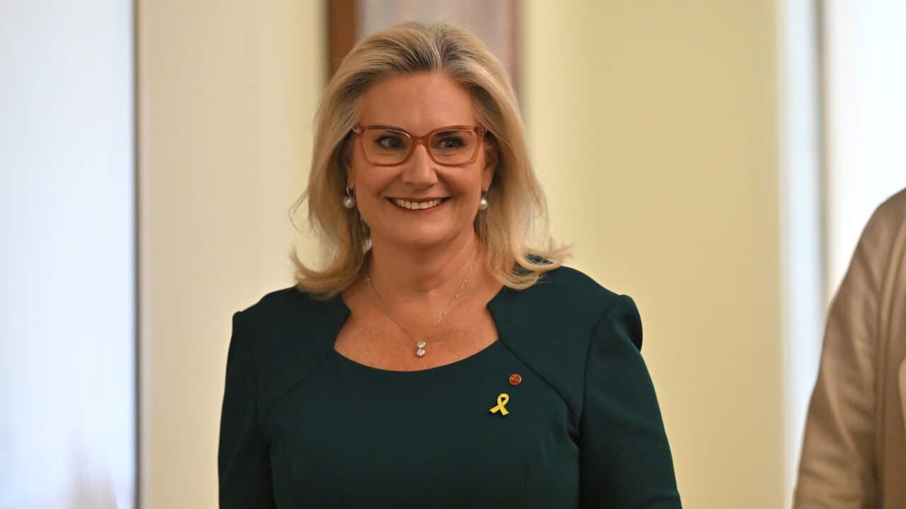 A middle-aged white woamn with blonde hair and glasses smiling