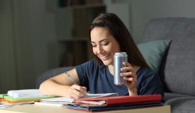A person drinking an energy drink while studying.