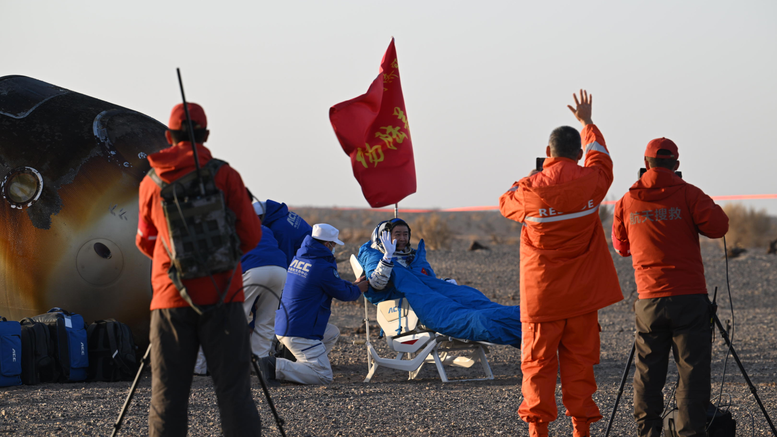 Photo of Chinese astronaut being taken out of a return capsule in the desert