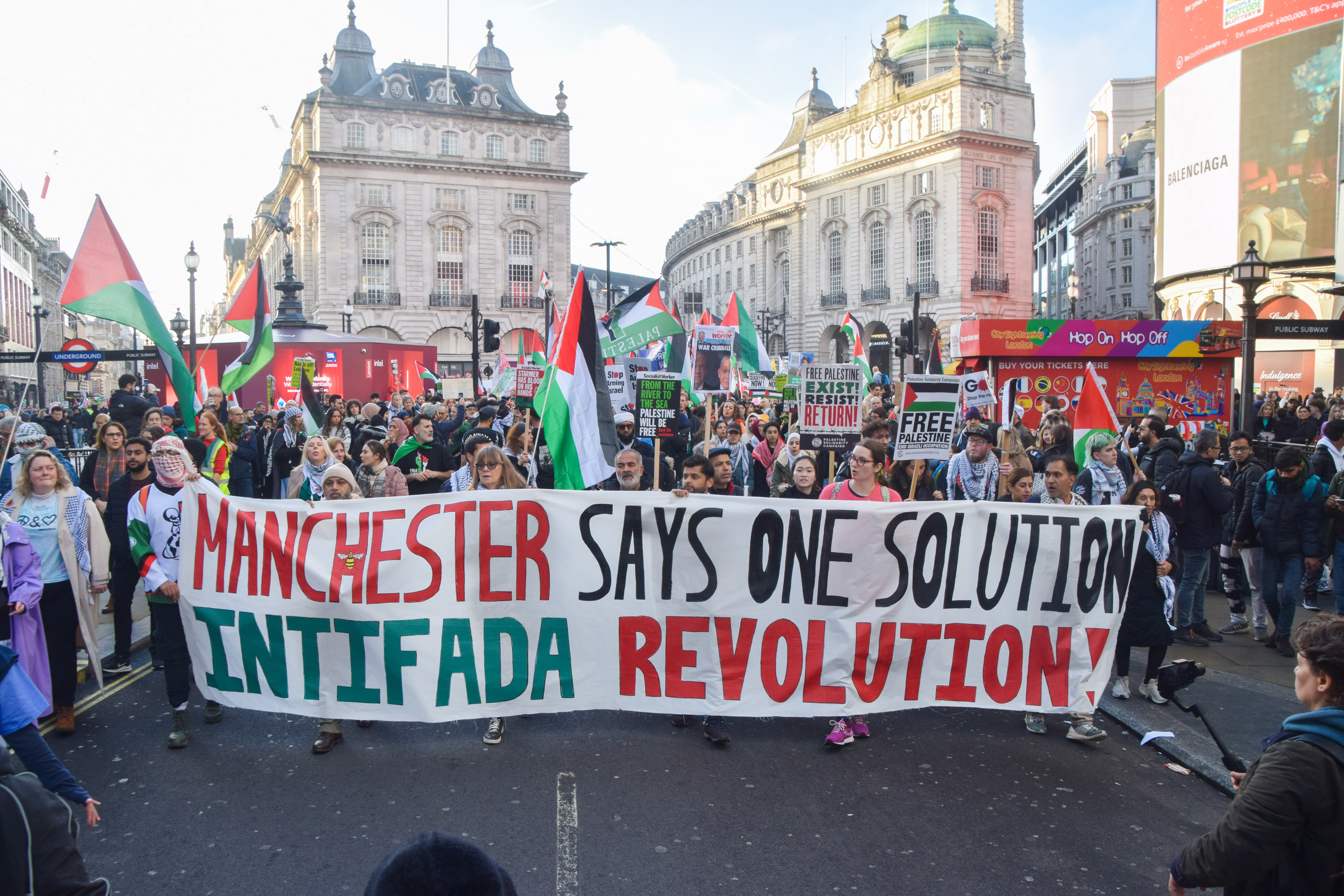 Protesters in London hold a banner that reads "MANCHESTER SAYS ONE SOLUTION INTIFADA REVOLUTION!".