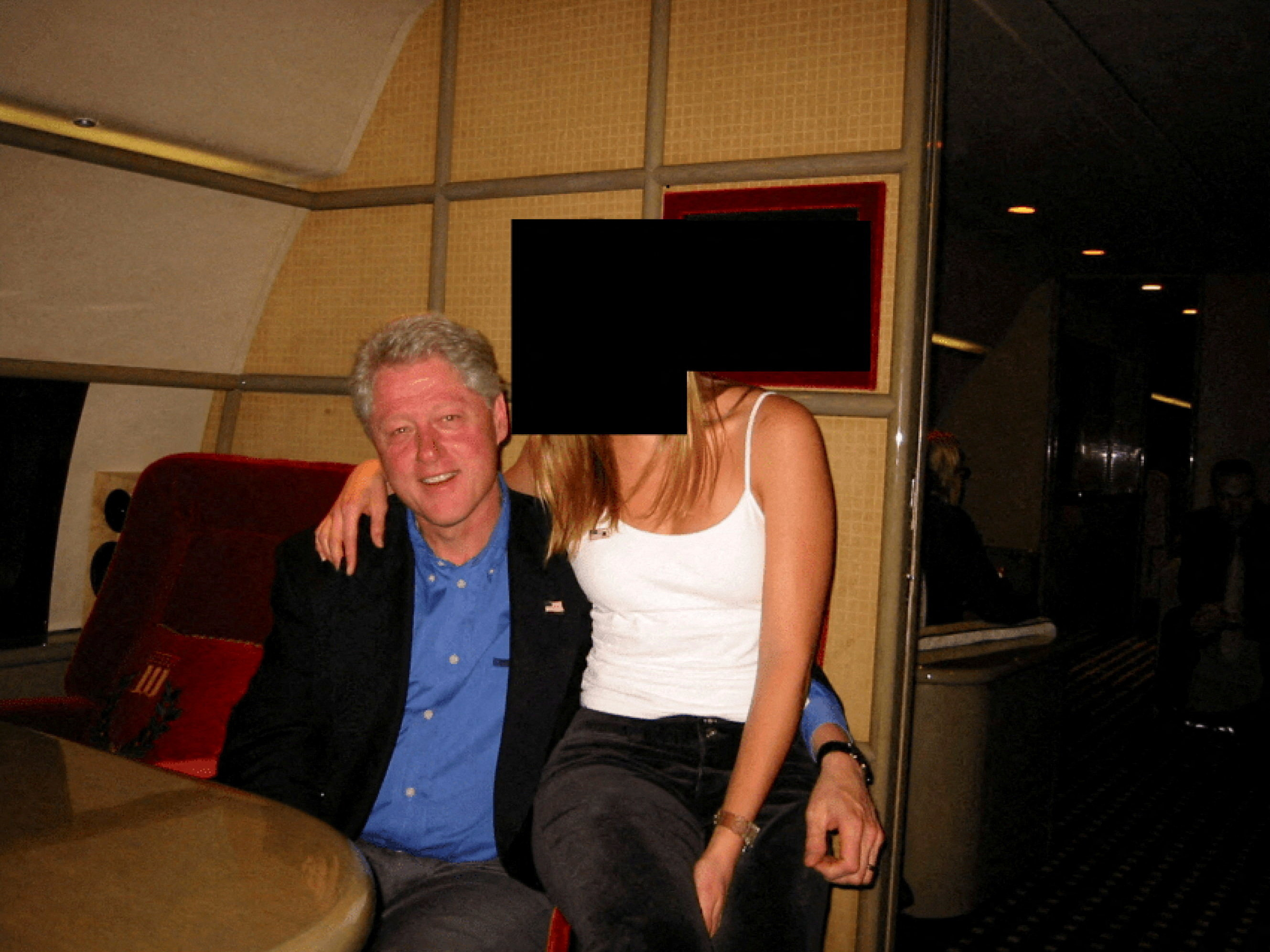 Former U.S. President Bill Clinton and a woman with her face redacted by the source are seated, with the woman's arm around Clinton's shoulder.