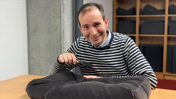 A man holding a magnifying glass inspects ancient clay tablets
