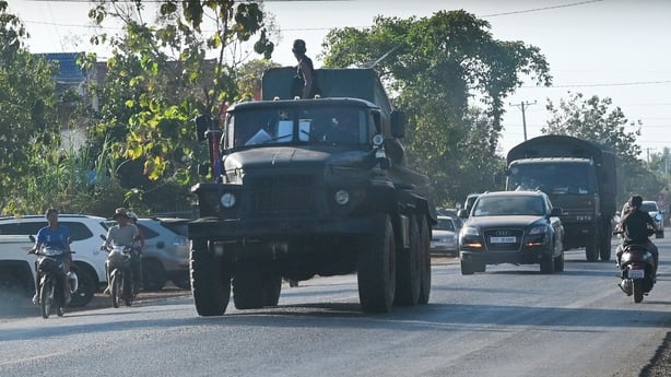 A soldier stands on a military vehicle on a street in Cambodia.