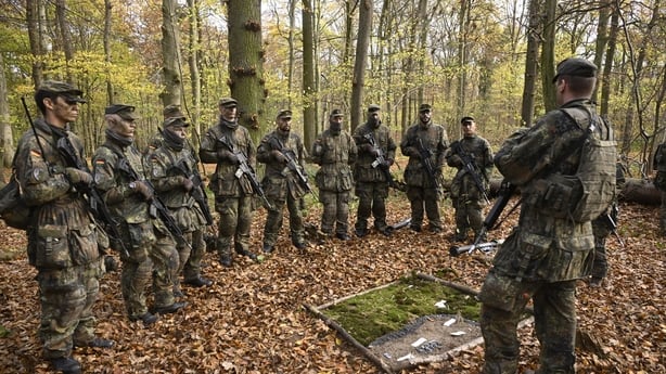 A group of German recruits stand in a forest during a basic training day.