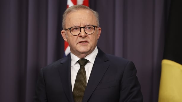 Prime Minister Anthony Albanese standing in front of an Australian flag.