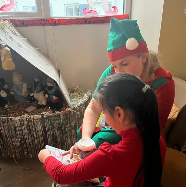 A child support worker for Focus Ireland reads a book with a young girl