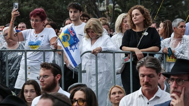 Mourners observe a moment of silence as they attend the memorial held for the victims of a shooting at Bondi Beach in Sydney 